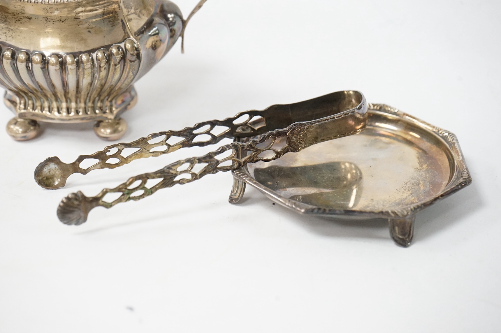 An Edwardian demi fluted silver two handled sugar bowl, Birmingham 1901, together with a pair of silver sugar tongs and a small silver dish, 7.1oz. Condition - fair